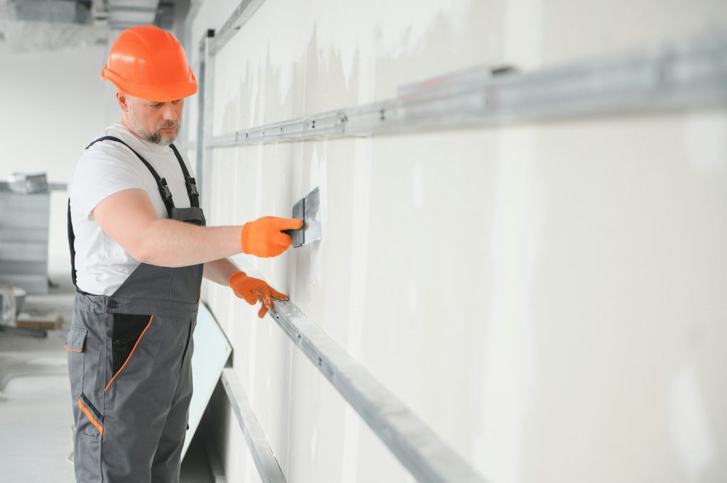 apartment interior construction - worker plastering gypsum board wall