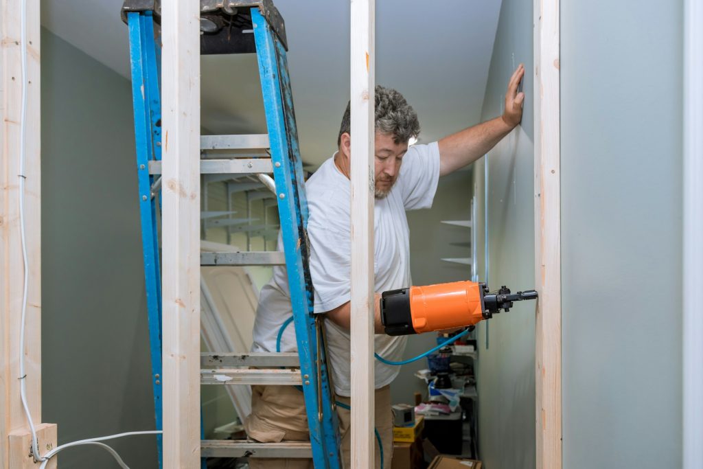 Building a home using an air hammer to nail wooden beams to framework of house during construction